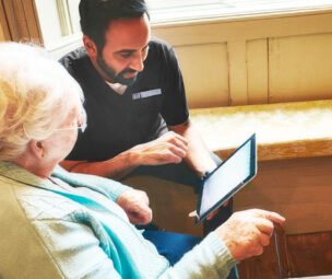 Carer-with-iPad-and-old-lady How does care work? Home Care in Leighton Buzzard. Care in Oxford. Care in Kings Langley.