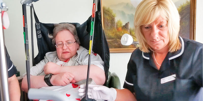 Carer with Margaret in a hoist 1st Homecare - Home Care Visits and Live-in care in Oxford.